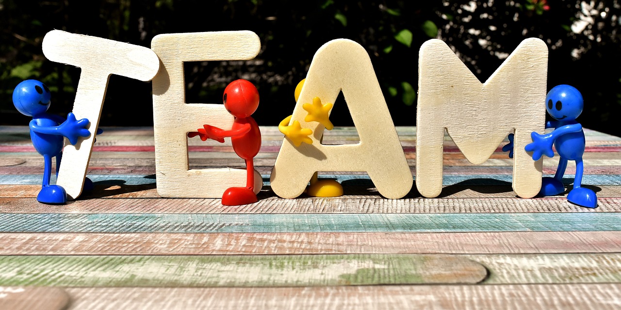 T E A M wooden letters are each held by smiley plastic human models